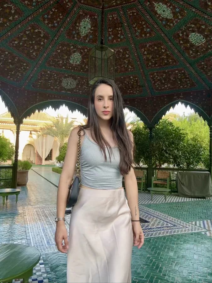 A woman in a courtyard in a light top and a long skirt