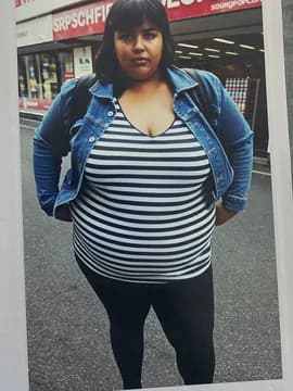 A woman outside a supermarket in a striped top and denim jacket